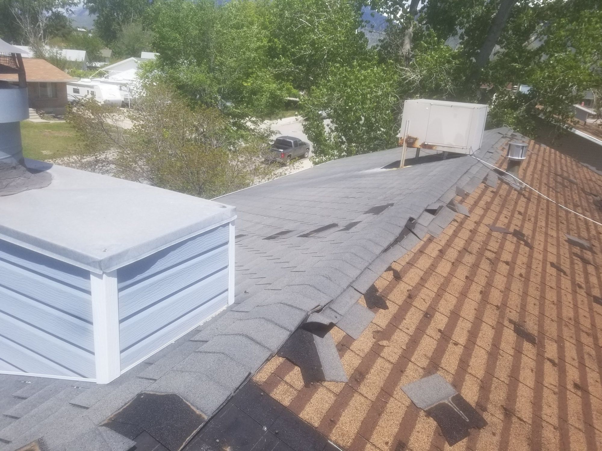 Gray asphalt shingle roof with torn and missing tabs, sided dormer box and rooftop cooler unit, in Draper, UT