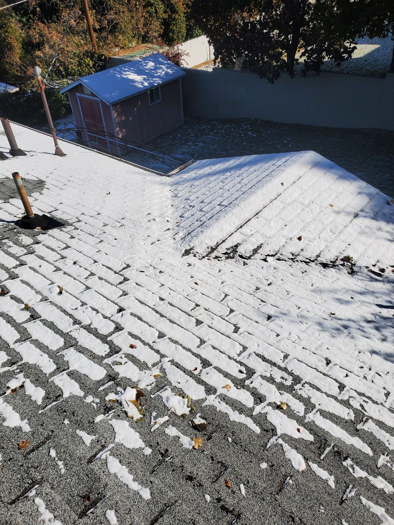 Light snow on asphalt shingle roof with pipe boot, hip line, and backyard shed below, in Provo, UT