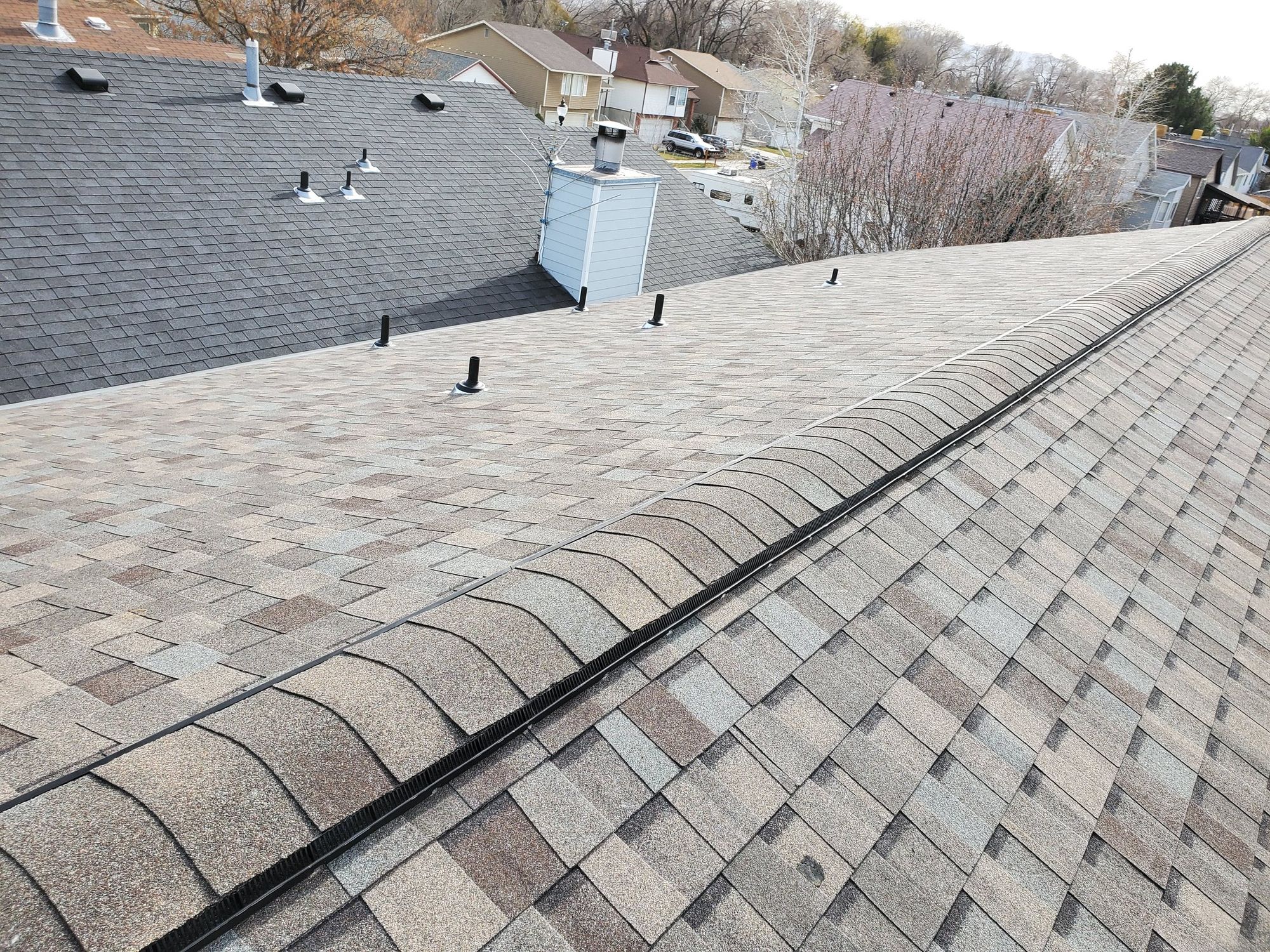 New asphalt shingle roof with vented ridge cap, black pipe boots and a sided chimney chase