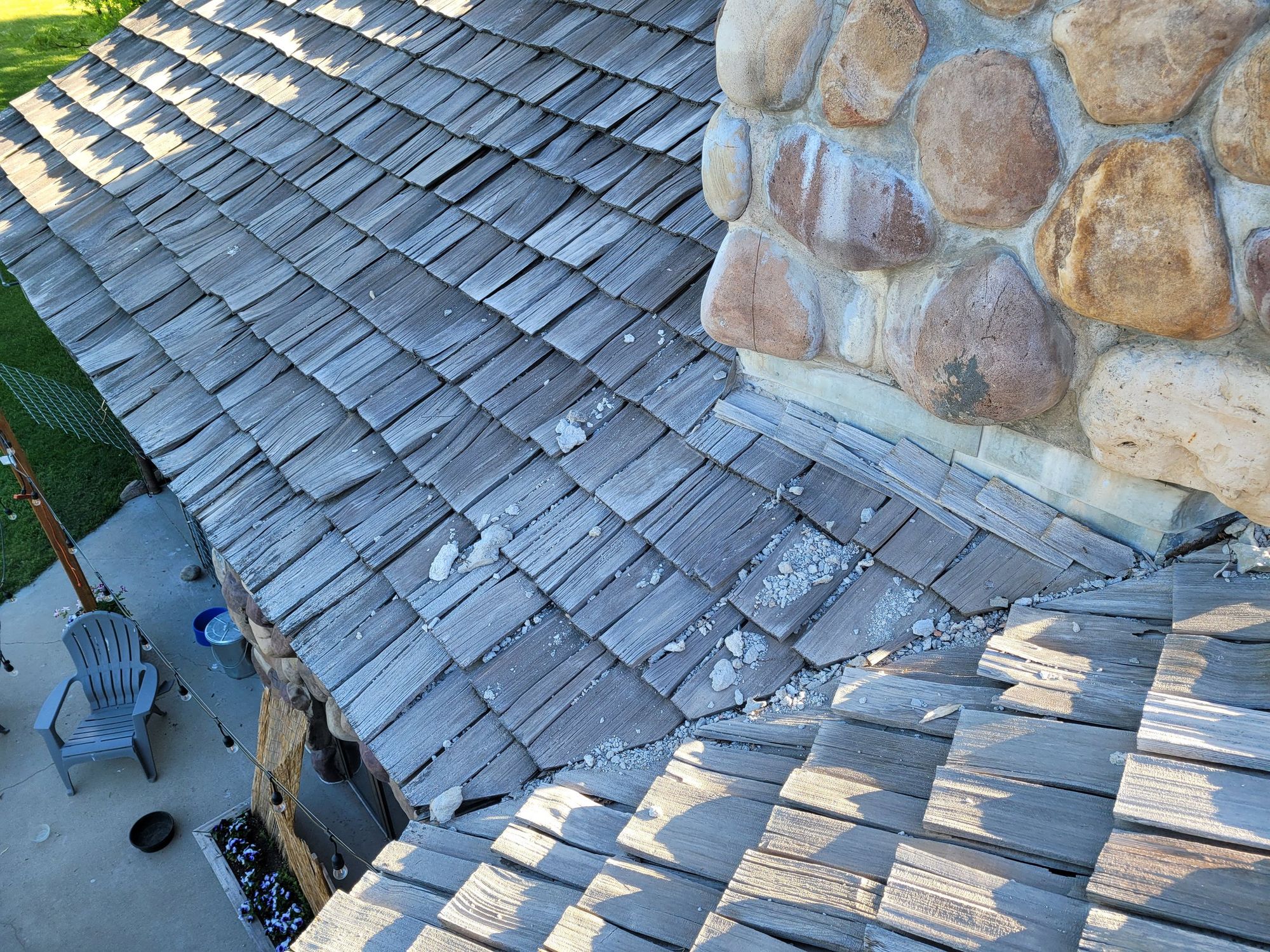 Aged split cedar shake roof with scattered mortar debris next to a river-rock stone chimney, in West Jordan, UT