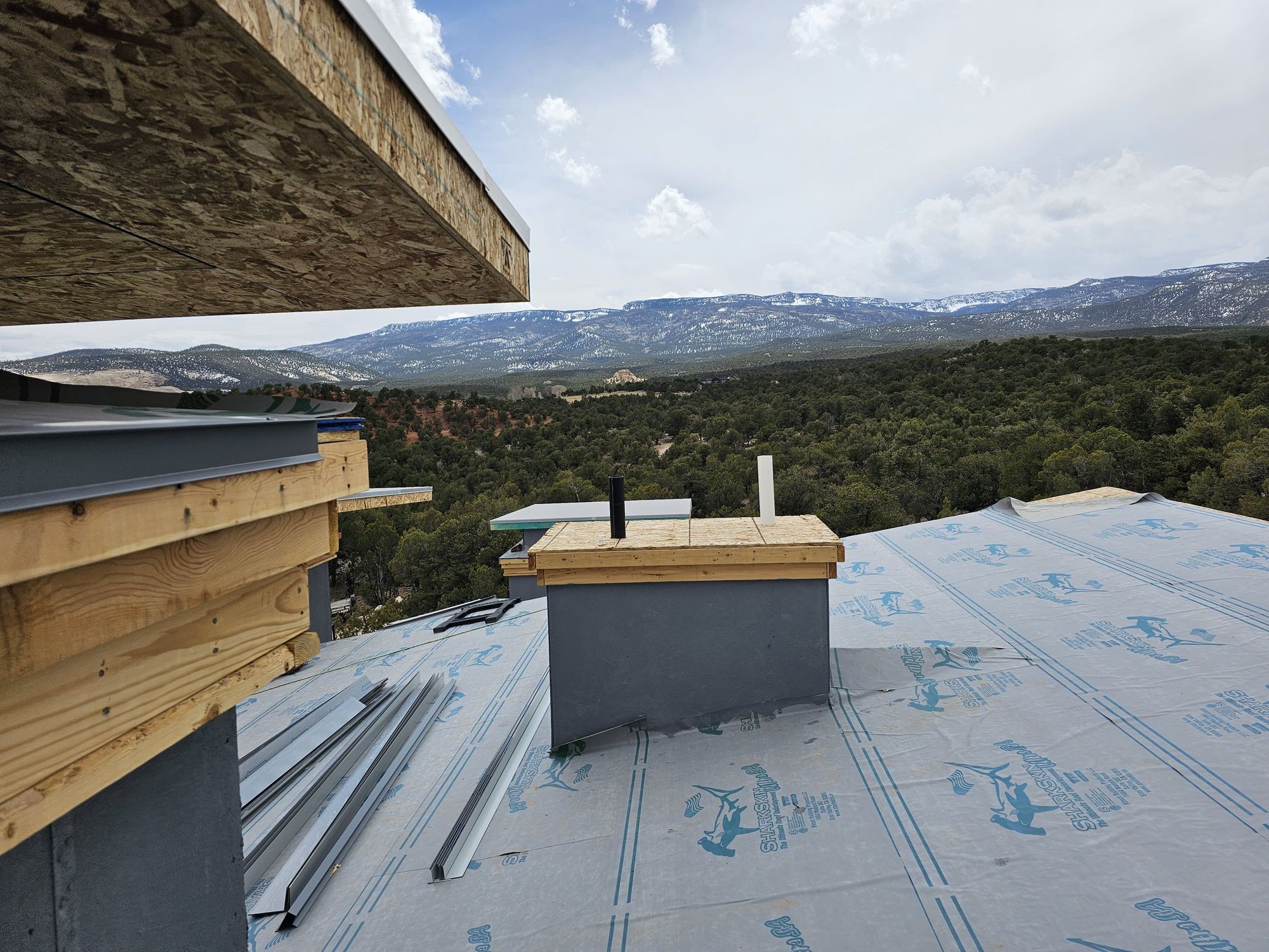 Roof deck covered in synthetic underlayment with wrapped chimney chase, staged metal trim and mountain view