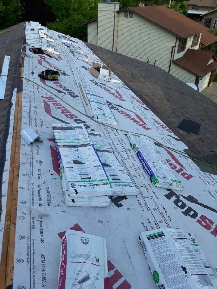 Roof covered in printed synthetic underlayment with shingle bundles staged along the slope before installation