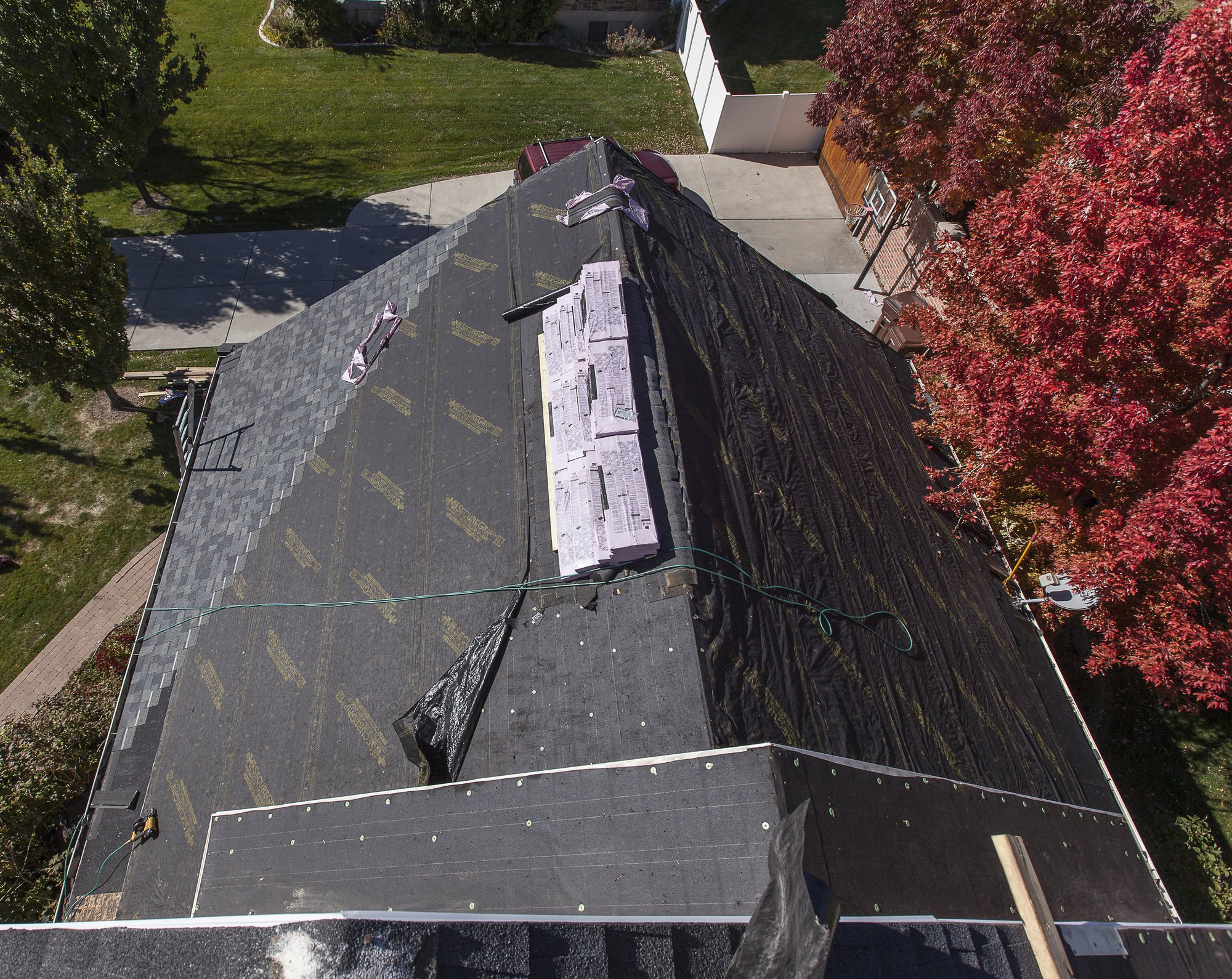 Drone view of a house roof covered in underlayment with new asphalt shingles started and bundles on the ridge, in Vineyard, UT